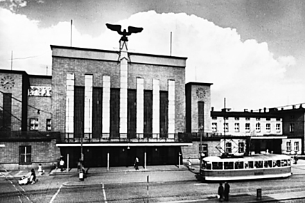 Budova nádraží na snímku z roku 1964. Železničářské okřídlené kolo doplnila pěticípá hvězda.  Interiér moderní odbavovací haly je doplněn o historickou sgrafitovou výzdobu. Víte, kdo je jejím autorem? Napište nám na redakce@olomouc.cz. Nejrychlejší správná odpověď bude odměněna volňáskem do Premiere Cinemas. (Soutěž už má výherce, nejrychlejším z vás byl Jiří Stránský)