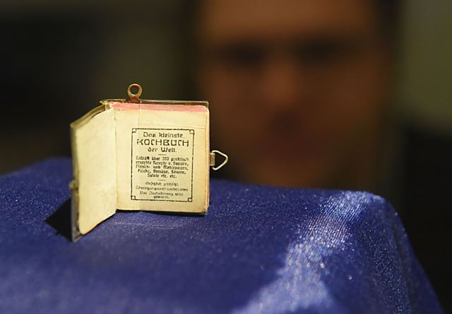 Na snímku je nejmenší kuchařka z roku 1906 v ČR a pravděpodobně jedna z nejmenších na světě s rozměry 24 krát 22 milimetrů se sto recepty na 136 stranách.