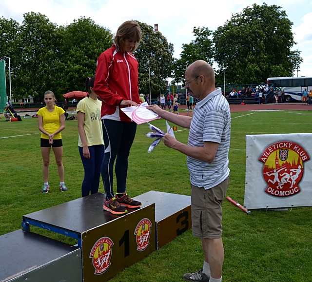 Domácí dorostenka Michaela Gieselová na stupních vítězů. Zvítězila ve skoku dalekém (545 cm), na 100 m překážek byla druhá (15,56 s) a na bronzovou příčku dosáhla v běhu na 300 m překážek (46,04 s). Certifikát o úspěšném umístění a upomínkový dárek předává předseda Atletického klubu Olomouc Miroslav Hrabal.