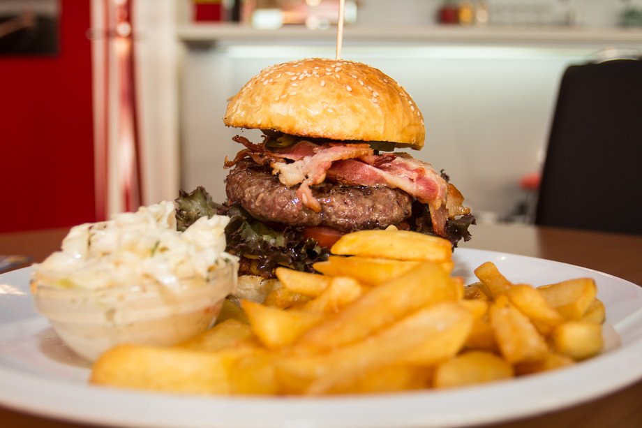 Víte, jak se správně jí hamburger? Na příbor rovnou zapomeňte! Tři prostřední prsty patří nahoru na bulku, malíčky a palce zase pěkně dolů. Tak celý hamburger působí kompaktně a nemáte problém si vychutnat všechny ingredience pohromadě. O to tady totiž jde :) A když vám poteče omáčka přes prsty, tak to není faux pax - máte přece ubrousek!