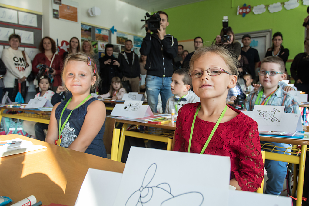 Usměj se, nabádá holčička vlevo svou čerstvou sousedku a ukazuje na foťák. Třeba z nich budou kamarádky na celý život. Dnes je pro prvňáky opravdu velký den.