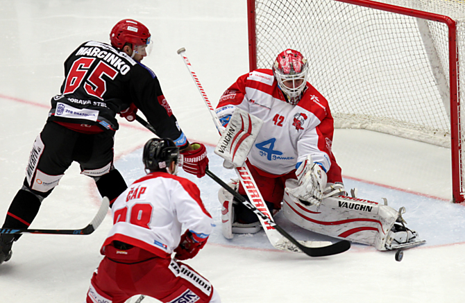 Brankář HC Olomouc Branislav Konrád likviduje šanci svého krajana v dresu Třince Marcinka.